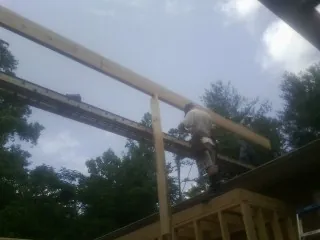 Carpenter setting a ridge beam over a new addition frame — Ice Dam Removal by Roofing Brothers in Fulshear