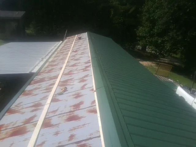 Old rusted panels beside newly installed green metal roofing — Wind Damage Roof Repair by Roofing Brothers in Fulshear
