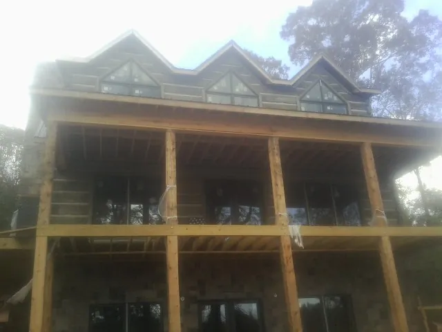 Dormers and porch framing on a large log home under construction — Roof Coating work by our crew in Fulshear