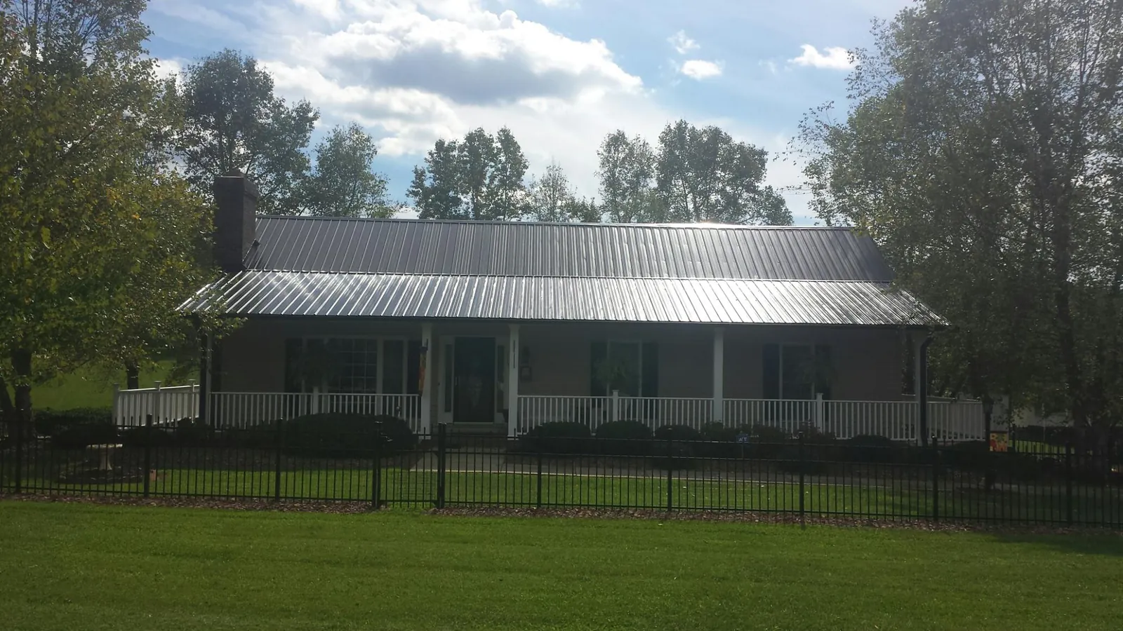 Gray metal roof on a brick ranch with a full width front porch — Gutter Guard Installation work by our crew in Fulshear