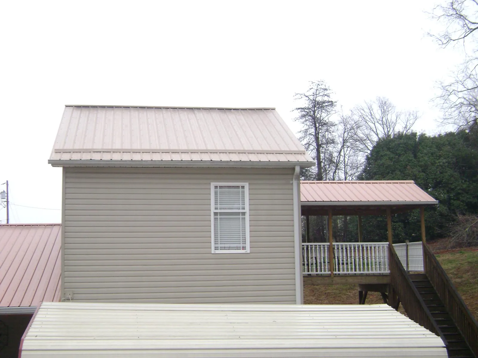 Tan metal roofs on a two story addition and attached porch, from a Roof Replacement job in Fulshear
