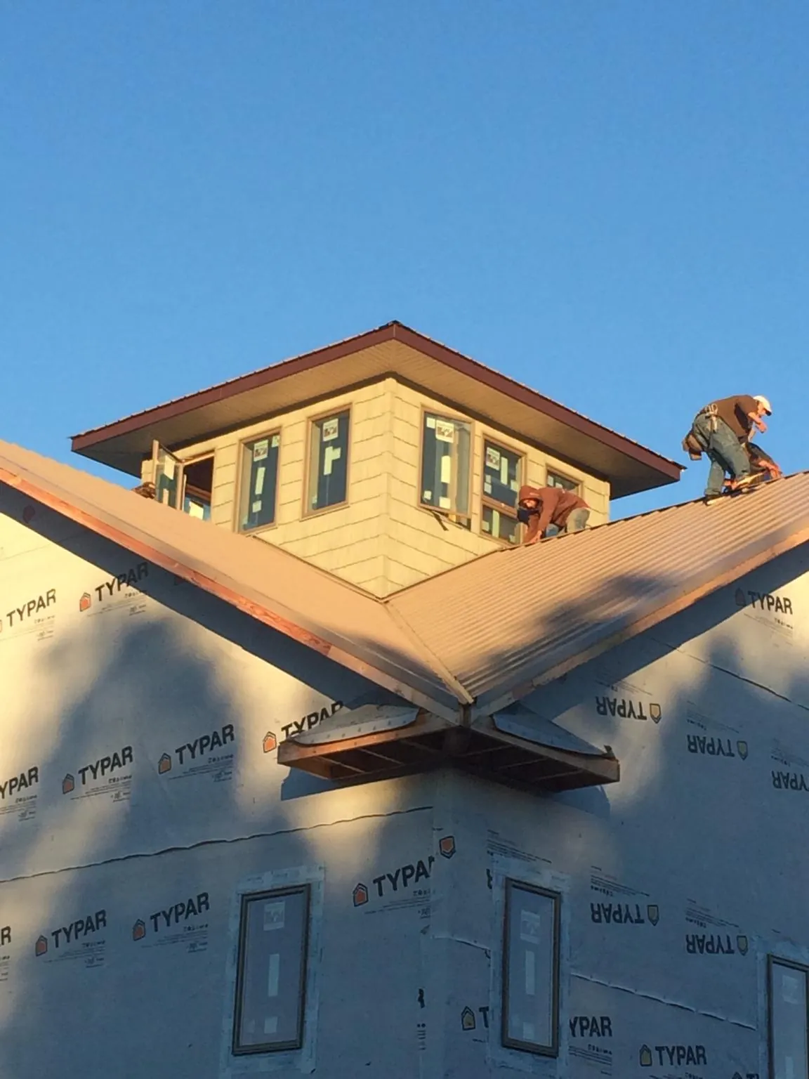 Roofers working around a rooftop cupola on a new metal roof at sunset — Roof Waterproofing in Fulshear by Roofing Brothers